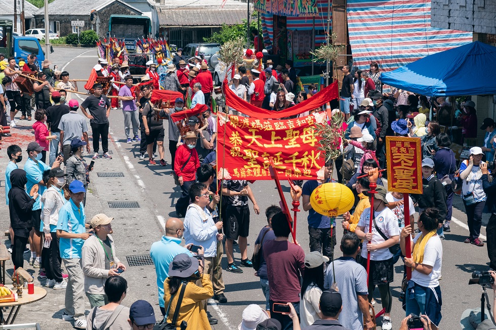 媽祖與我們的工作假期――這場不喊口號的遊行，大夥舉著協力完成的布條走進遶境隊伍中。參與者們的共筆圖文影像紀錄，對外呈現在台灣文博會一隅，展出現場設置紅圓桌，邀請觀眾嗑瓜子交流。（攝影／梁家瑋）