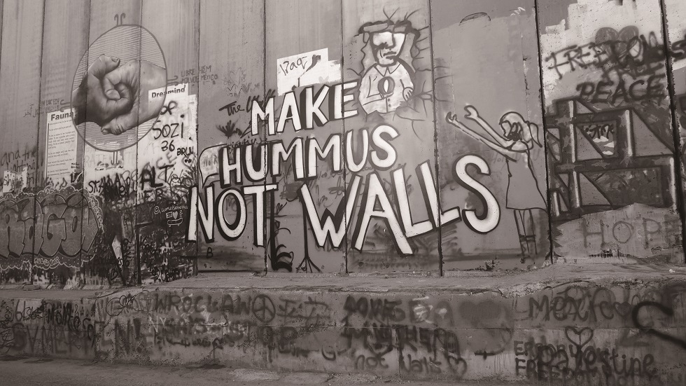 隔離牆上的塗鴉寫著：「Make Hummus Not Walls」（做鷹嘴豆泥，而不是牆）。鷹嘴豆泥（Hummus）是以巴皆有的家常食物，因而常被作為和平、族群融合的象徵。