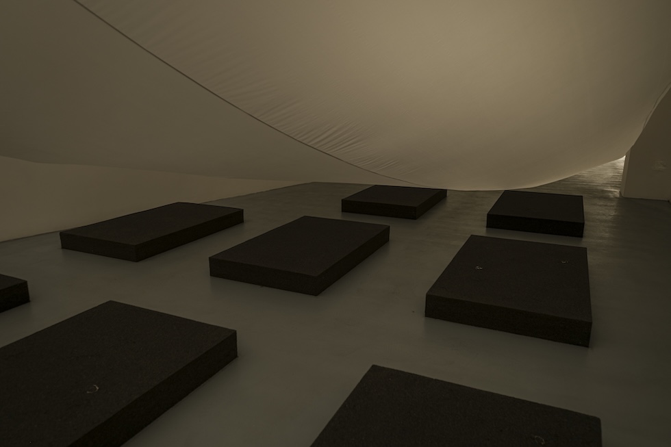 「No. 108」展中另個較暗的空間裡，有個氣囊構成的通道。通道的底部裝置了沙堆。