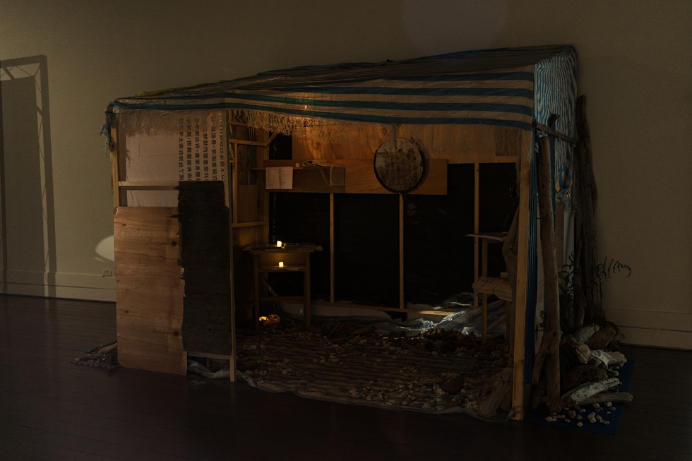 展場中的Talo'an(工寮)裡陳列著道叔與冉而山劇場的歷史資料,其中包括一本在 923 洪水後被泥水灌入、影像逐頁模糊的相簿。而工寮裡的佈置都是道叔從海邊撿拾來的飄流木及石頭。(攝影/鄭亦婷)