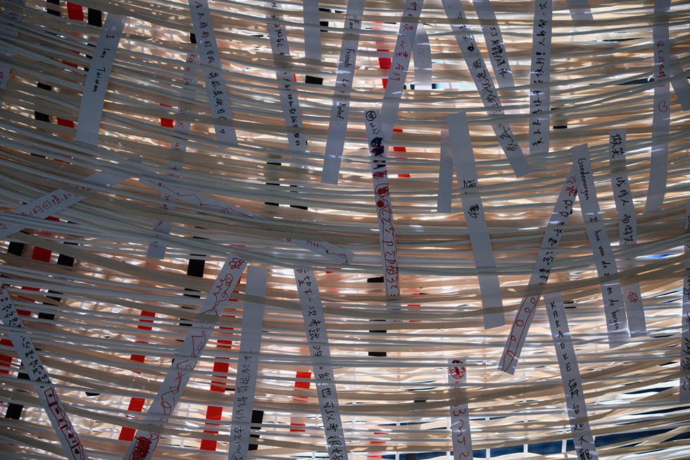 觀眾將自己的故事寫在紙條上編入經線裡。(攝影/鄭亦婷)