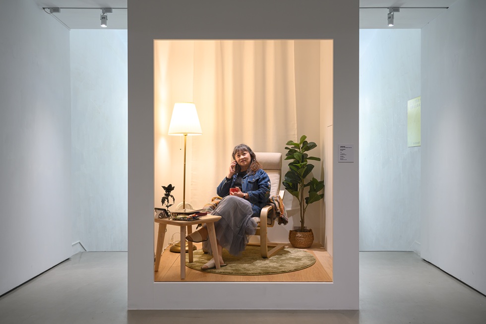 《母親凝視過你》,展場中一支署名「媽媽」的電話不定時響起,觀眾若願意可自行接聽;作品徵集的素人媽媽,於另一處居家場景櫥窗內即時演出,電話那端的聲音正是來自這裡。有章藝術博物館「陳美玲」展,2025。(明日和合製作所提供,攝影/上圖王欣翮、下圖ANPIS FOTO王世邦)