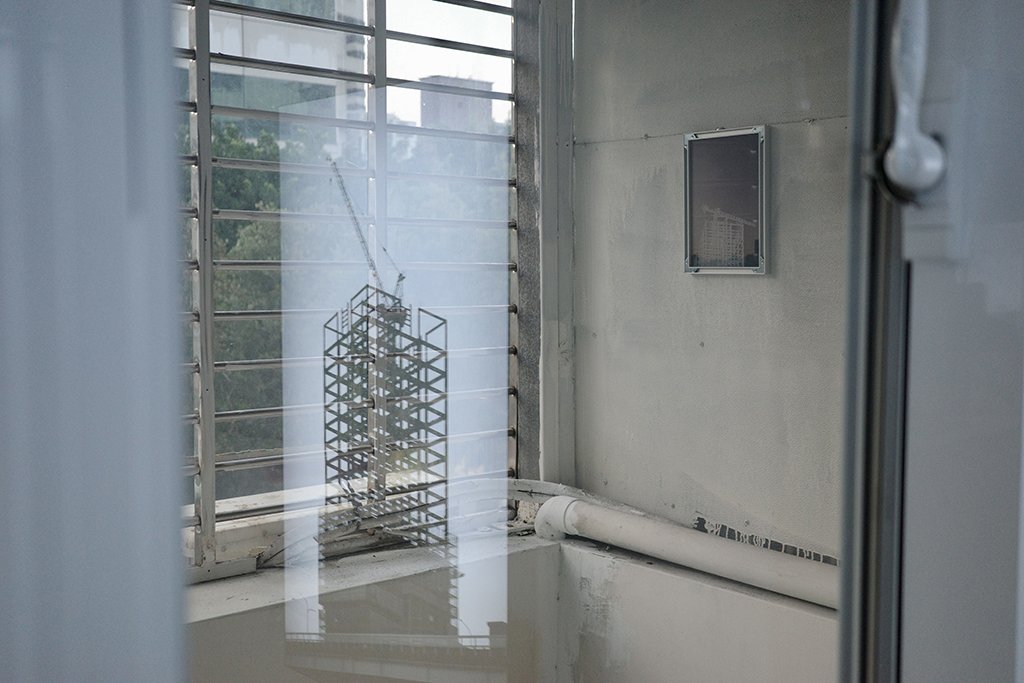 作品「攀爬的輪廓」系列（右）位於陽台空間，作品「攀爬架」系列攝影顯現在窗戶的倒影中。（攝影／林裕軒）