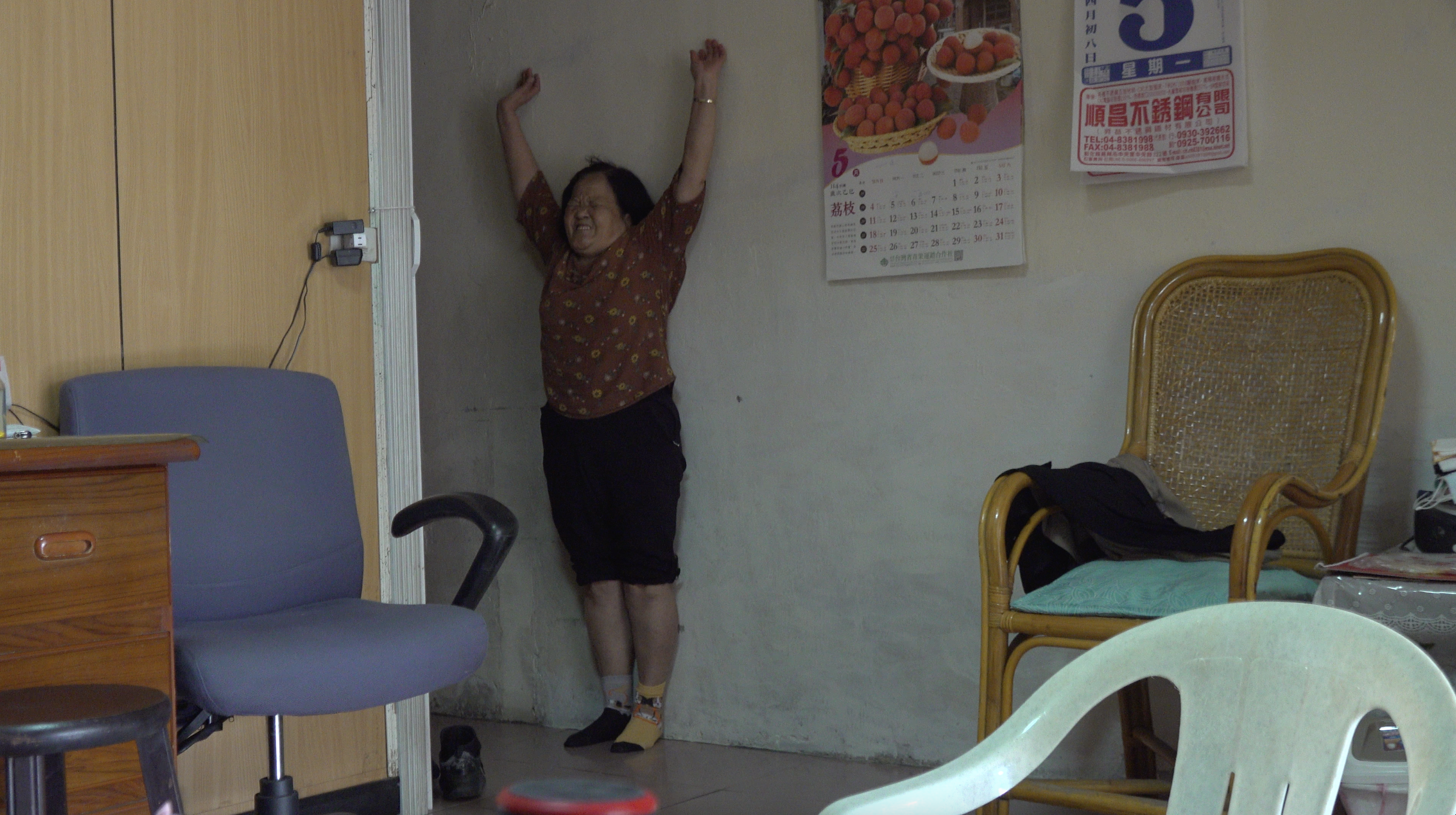《一人份生活》劇照：春花姨正在拉筋。作品完成後，蒲公英的社工莊豪隆帶著筆電到春花姨家，與她一起觀影。